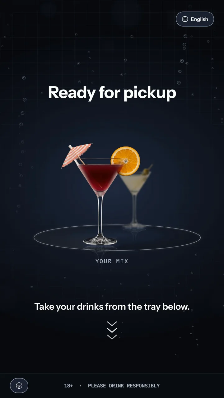 Ready for pickup: two drinks on a turntable at life size, Your Mix in front, over a lab grid with bubbles, and the instruction Take your drinks from the tray below with chevrons pointing down.